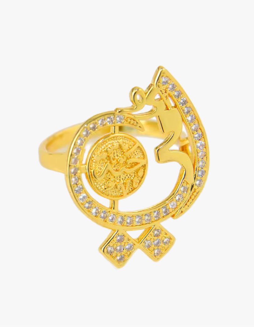 A gold-plated ring featuring a crescent moon and star design embellished with small clear crystals, with a circular medallion on the band, set against a plain light gray background.