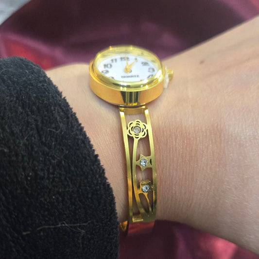 Gold wristwatch on a person's wrist with a blurred background