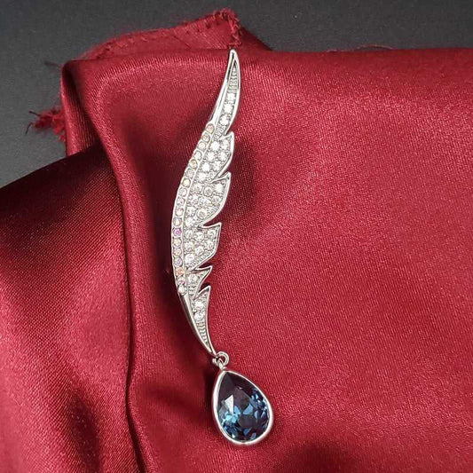 Timeless Feather Brooch in Silver finish, with cubic zirconia stone on and a blue pear-shaped stone