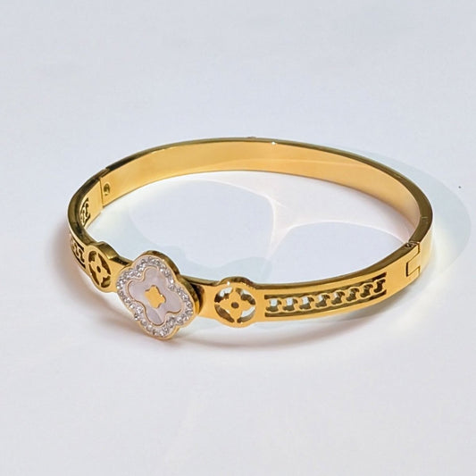 Gold bracelet with intricate design on a light gray background