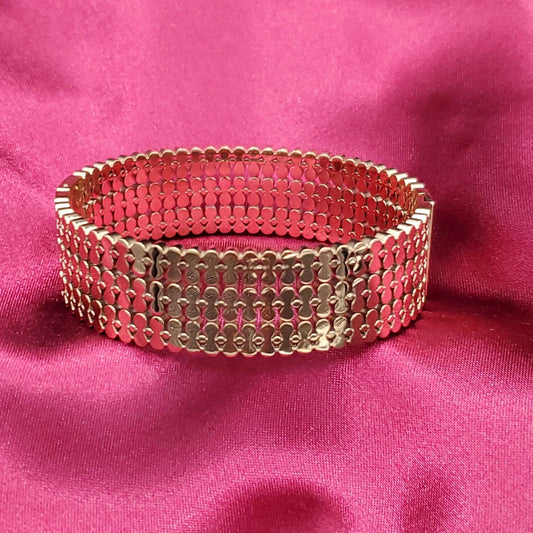 Wide Bangle in Gold finish on a pink background